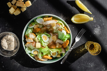 Caesar salad with chicken in a plate on a dark background
