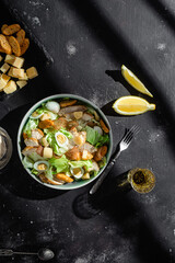 Caesar salad with chicken in a plate on a dark background