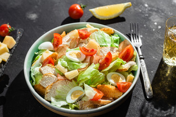 Caesar salad with chicken in a plate on a dark background