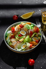 Caesar salad with chicken in a plate on a dark background