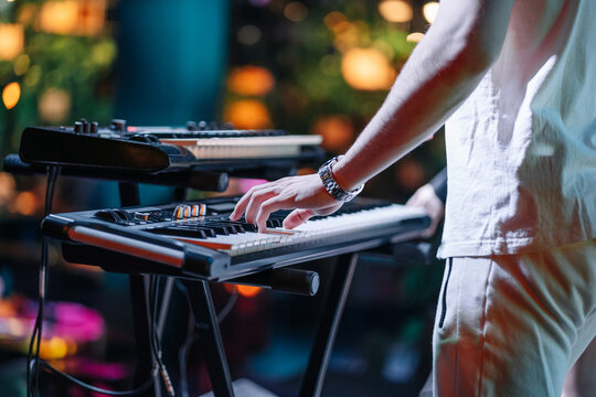 Close shooting of a keyboardist musician at work at a concert. Keyboardist play keyboard on stage.