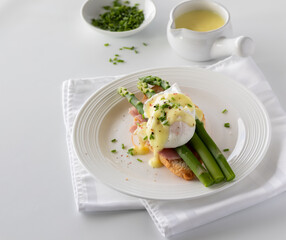 A plate of eggs benedict topped with hollandaise sauce and chives.