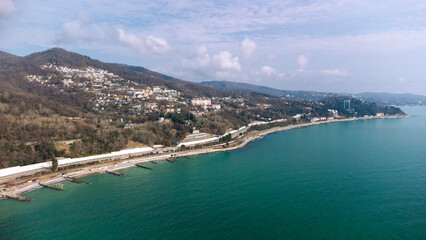 Fototapeta na wymiar Aerial view of the southern city along the seashore. Road and railway along the sea line. Russia, Sochi, Red Storm.