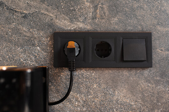Close-up of black plug connected to socket on marble background.