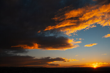 Fototapeta na wymiar Natural landscape. Reflection of sunset colourful light on dark cloudy sky.