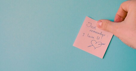 Just remember - I love you - male hand is pasting a reminder sticker.