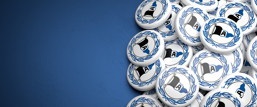 Logos of the German Soccer Club Arminia Bielefeld on a heap on a table. Copy space. Web banner format