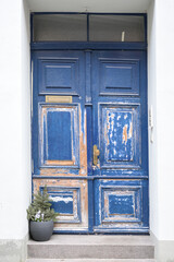 Blue wooden front door in need of renovation with partially sanded paint in the entrance of a historic old town house in Lubeck, Germany
