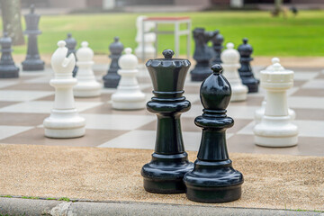 street chess. large black and white chess pieces and outdoor game board close-up