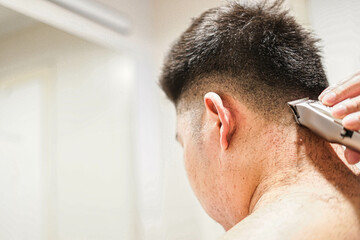 Obraz premium Blurred, Man using electric hair clipper for self hair cut.