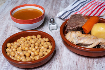 Cocido Madrileño, stew of chickpeas, vegetables, beef, chicken, chorizo and bacon typical of Madrid, served in separate dishes, soup, chickpeas and meat.