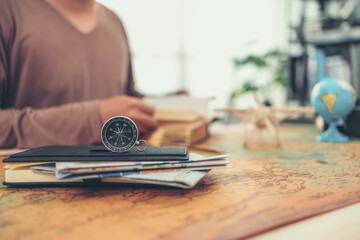 Magnetic compass on abook and road map inside on world map and  man read a travel book. Travel ,...