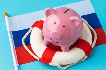 Piggy bank, lifebuoy and flag on a colored background, the concept of saving the Russian economy