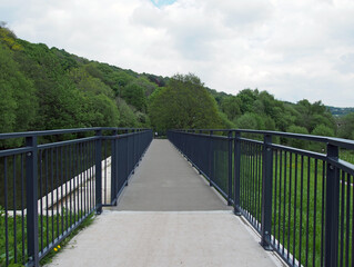 Fototapeta premium raised pedestrian footbridge over the brearley fields canal spillway next to the river calder in west yorkshire