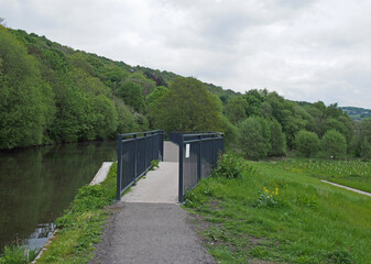 Fototapeta premium raised pedestrian footbridge over the brearley fields canal spillway next to the river calder in west yorkshire
