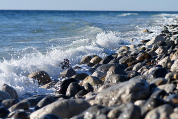 Sea waves striking at white big rocks at the sea beach on windy weather. 