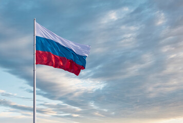 Waving Russian flag against a blue sky with clouds and empty space for text. Room for text. National flag of the Russian Federation.