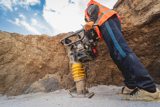 Worker uses a portable vibration rammer at construction of a power transmission substation