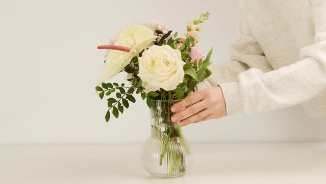 Florist adding new flower to bouquet in a vase, creating composition. Fresh cut flowers for decoration home. Decor and small business concept.