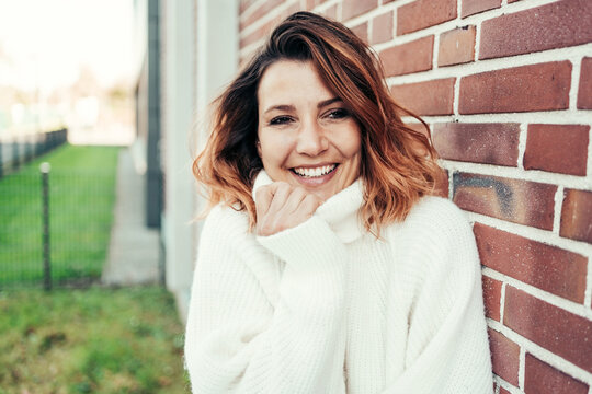 Happy vivacious woman snuggling into a woolly turtleneck sweater