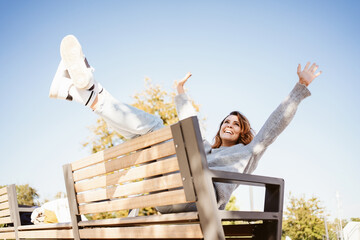 Exuberant joyful young woman kicking her legs and arms in air