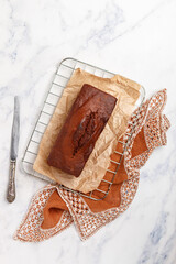 Freshly baked homemade banana chocolate loaf. Pound cake with chocolate pieces in close-up. A whole dessert on baking paper. Marble background. Selective focus, top view