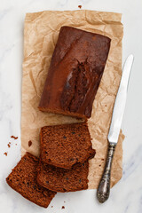 Freshly baked homemade banana chocolate loaf. Pound cake with chocolate pieces in close-up. Dessert slices on baking paper. Marble background. Selective focus, top view