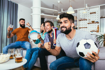 Excited friends watching football game and holding beer and popcorn