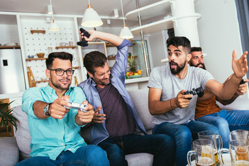 Smiling male friends with gamepads and beer playing video game at home © Mediteraneo