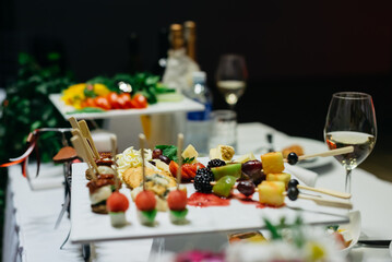 A white ceramic coaster with hors d'oeuvres on the wedding table..Appetizers on plates. Catering service. Wedding welcome food.
