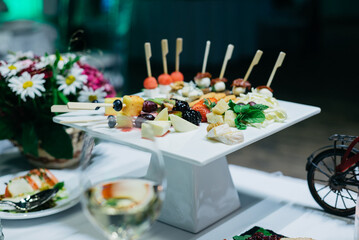 A white ceramic coaster with hors d'oeuvres on the wedding table..Appetizers on plates. Catering service. Wedding welcome food.