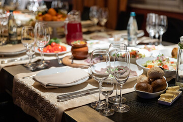 Table setting for a banquet or celebration.Empty glasses for alcoholic beverages, wine and juice, set the table.Cloth napkins on a white platter and cutlery on the table.Cold appetizers and salads