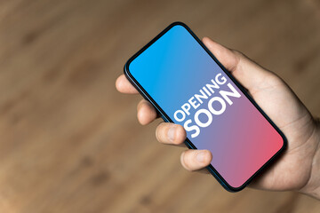 Opening soon - hand holding a phone