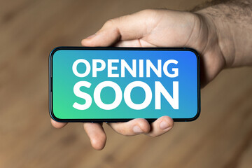 Opening soon - hand holding a phone