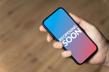 Reopening soon - hand holding a phone