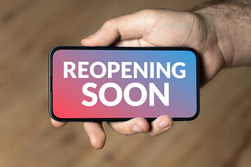 Reopening soon - hand holding a phone