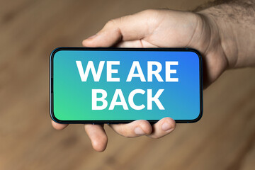 We are back - hand holding a phone