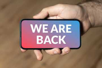 We are back - hand holding a phone