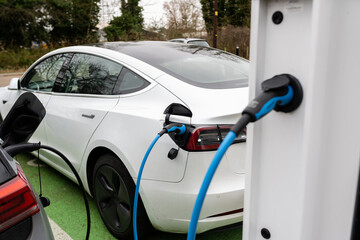 Electric car charging at plug in charge station in a public car park in Suffolk, UK