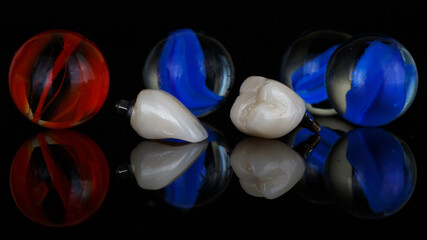 ceramic dental crowns with bright glass red and blue balls on black glass