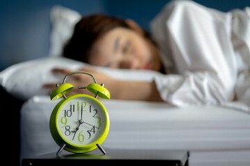 Young woman turning off alarm clock in morning late without looking clock. Relaxation and people...