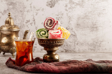 Traditional Turkish delight with Turkish tea on gray background. Ramadan Kareem celebration concept. Fragrant Turkish tea and Turkish sweets in national dishes.
