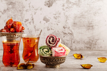 Traditional Turkish delight with Turkish tea on gray background. Ramadan Kareem celebration concept. Fragrant Turkish tea and Turkish sweets in national dishes.