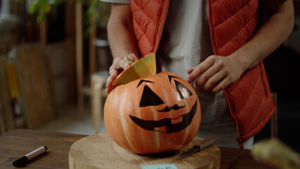 A young man and his friend sniff the top of the pumpkin