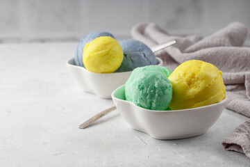 Various colorful scoops of ice cream in white bowls on a light background. Refreshing summer dessert. Homemade natural product. copy space,