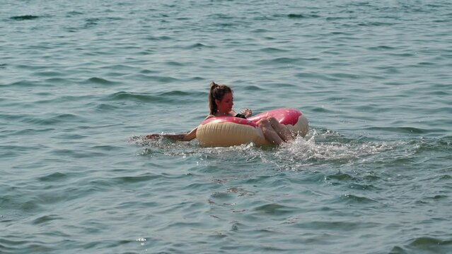 young woman in swimsuit swims on inflatable circle in sea in summer on vacation on summer day
