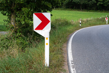 Road sign with a red arrow pointing to the right in a sharp curve