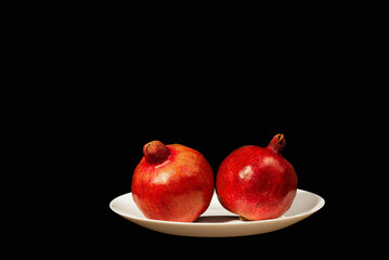 two fruits of ripe Georgian pomegranate on a plate