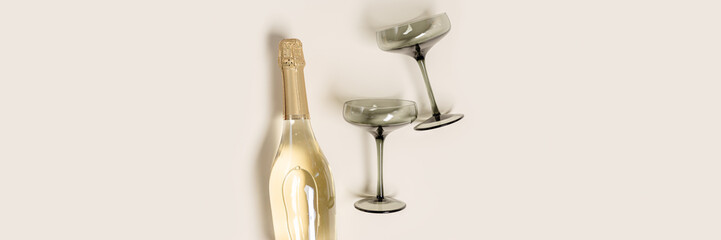 Champagne glasses tinted grey glass, Champagne or sparkling wine bottle on beige background....