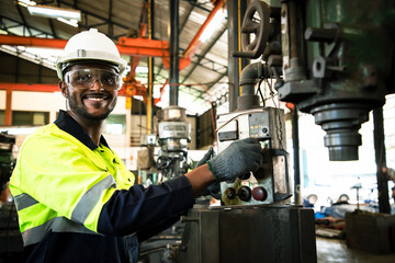 Africa American worker with lathe Machine and wearing safety goggles control lathe machine to drill...